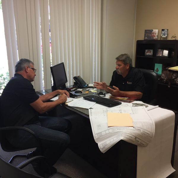 Two contractors sitting across a desk planning a project to build